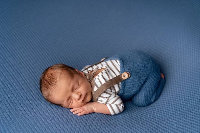 Neugeborener Junge beim Fotoshooting auf einer blauen Decke