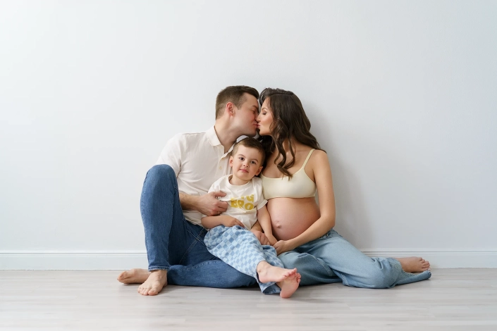Babybauchfotografie-familie-hamburg-tageslicht Familienbild auf dem Boden mit schwangerer Frau in Jeans und Tageslicht